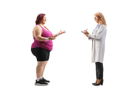 Full length profile shot of an overweight woman talking to a female doctor isolated on white backgroundの写真素材