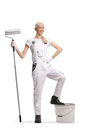 Happy cheerful female house painter stepping on a bucket isolated on white backgroundの写真素材