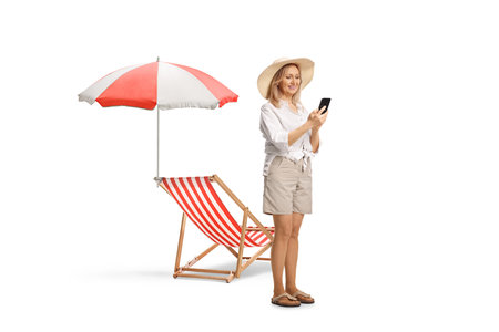 Happy middle aged woman on a summer vacation using a mobile phone isolated on white backgroundの写真素材