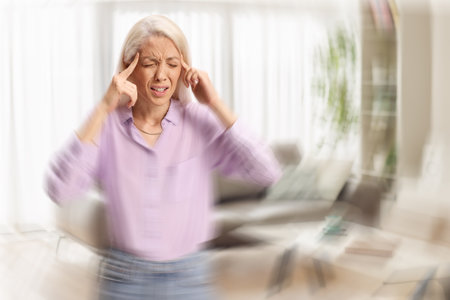 Young woman standing in a living room and feeling dizzyの写真素材
