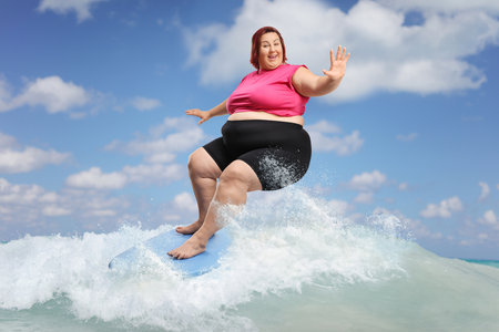 Corpulent woman riding a surfboard in the sea