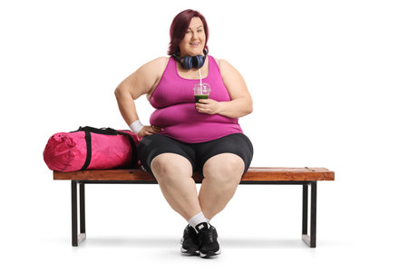 Woman sitting on a gym bench and holding a green smoothie, weight loss conceptの写真素材