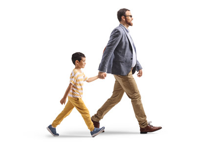 Father and a kid walking together and holding hands isolated on white backgroundの写真素材