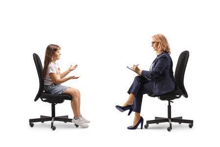 Little girl sitting in a chair and talking to a woman isolated on white backgroundの写真素材