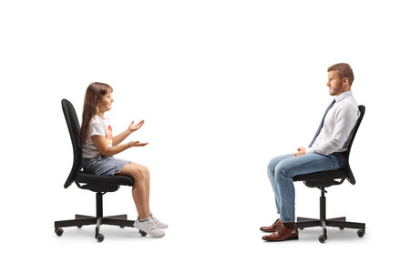 Child sitting in a chair and talking to a man isolated on white backgroundの写真素材