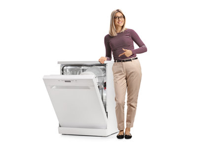 Smiling young woman pointing at a dishwasher isolated on white backgroundの写真素材