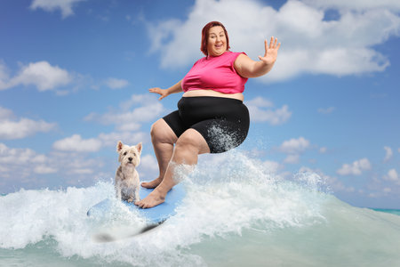 Big woman with a dog riding a surfboard in the seaの写真素材