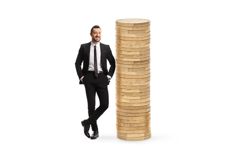 Full length portrait of a male economsit leaning on a pile of coins isolated on white backgroundの写真素材