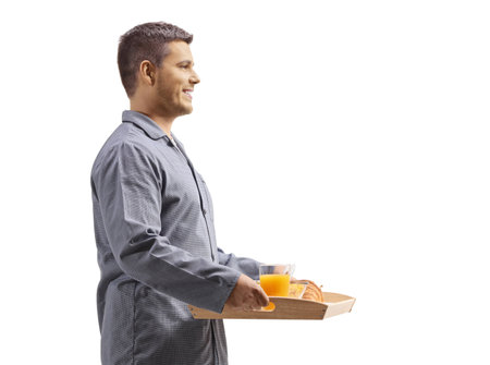 Man in pajamas holding a breakfast tray isolated on white backgroundの写真素材