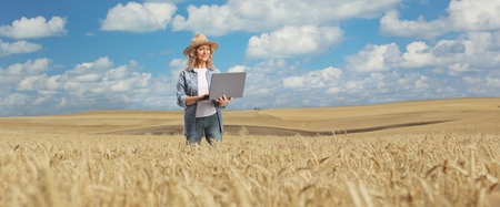 Female farmer using a laptop computer on a wheat field