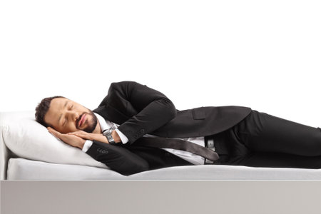 Businessman in a suit and tie sleeping on a bed isolated on white backgroundの写真素材