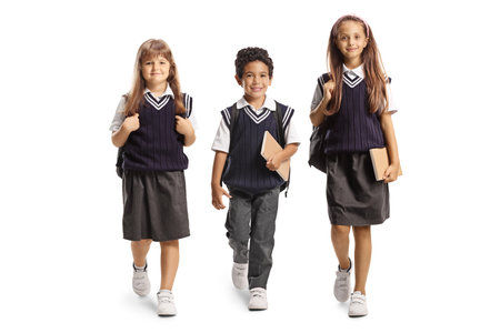 Children in school uniforms walking towards camera isolated on white background