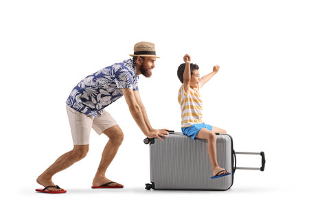 Father pushing son seated on top of a suitcase isolated on white backgroundの写真素材