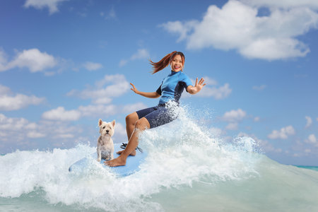 Woman in a wetsuit riding a surfboard in the sea with a dog
