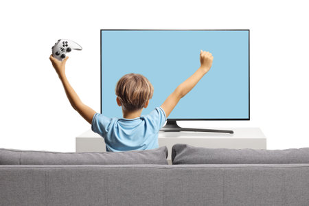 Rear view shot of a happy kid on a sofa and playing a video game isolated on white backgroundの写真素材