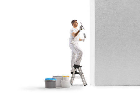 Plasterer on a ladder holding a trowel and plastering a wall isolated on white backgroundの写真素材