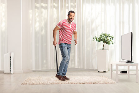 Full length shot of a man putting on shoes in a roomの写真素材