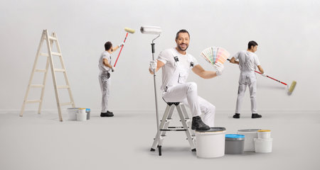 Team of painters at work with paint buckets and rollers painting a wallの写真素材