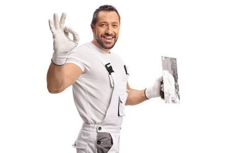 Plasterer holding a trowel with skim coat and gesturing ok sign isolated on white backgroundの写真素材