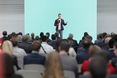 Event in a hall, man with a microphone on stage in front of people in the audienceの写真素材