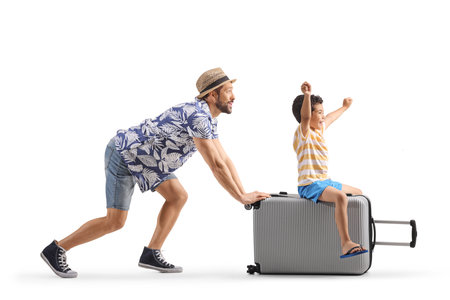 Man pushing a kid seated on a suitcase isolated on white backgroundの写真素材