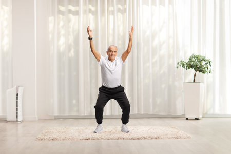 Elderly man exercising in a room with arms upの写真素材