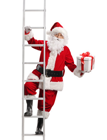 Portrait of Santa Claus holding a gift box and climbing a ladder isolated on white backgroundの写真素材