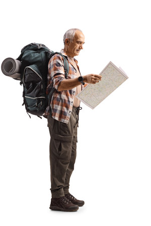 Elderly male hiker with a backpack reading a map isolated on white backgroundの写真素材