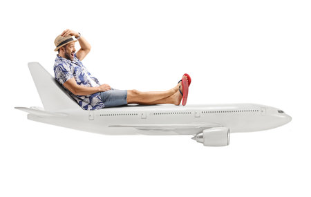 Full length profile shot of a male tourist sitting on top of an airplane isolated on white backgroundの写真素材