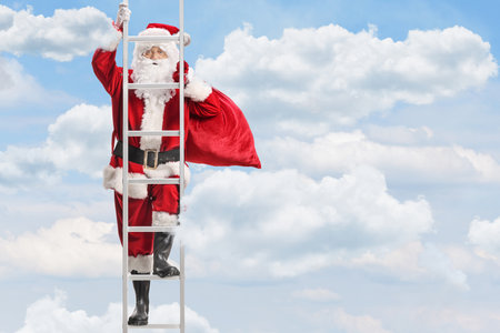 Santa Claus with a sack of presents climbing a ladder in the skyの写真素材