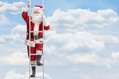 Santa Claus climbing a ladder in a blue sky with cloudsの写真素材