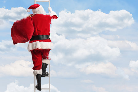 Rear view shot of Santa Claus with a sack climbing a ladder in the skyの写真素材