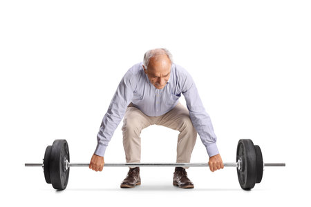 Casual elderly man trying to lift heavy weights isolated on white backgroundの写真素材