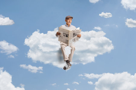 Pensioner sitting on a cloud and reading a newspaper in the skyの写真素材