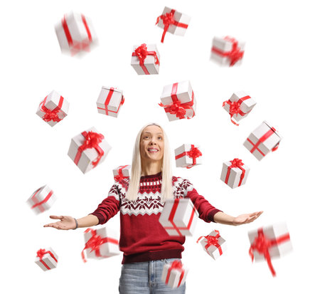 Happy woman in a red sweater looking at a rain of presents isolated on white backgroundの写真素材