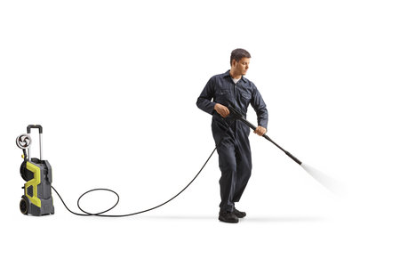 Worker cleaning with a high pressure washer machine isolated on white backgroundの写真素材