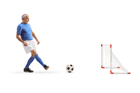 Full length shot of a mature athlete playing a football on a mini goal isolated on white backgroundの写真素材