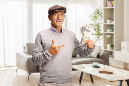 Pensioner pointing at stacks of money banknotes at homeの写真素材