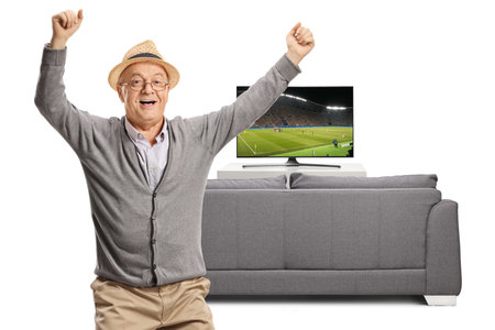 Happy elderly man cheering and watching a football match on tv isolated on white backgroundの写真素材