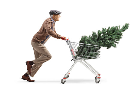 Full length profile shot of a pensioner running with a christmas tree in a shopping cart isolated on white backgroundの写真素材