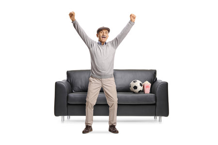 Overjoyed elderly man cheering for a favourite football team isolated on white backgroundの写真素材
