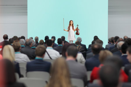 Girl performing with a violin on stage in front of audience