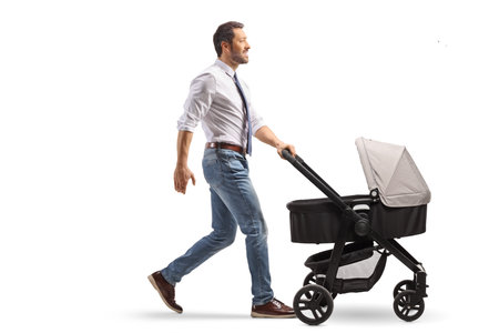 Full length profile shot of a professional father pushing a baby stroller isolated on white backgroundの写真素材