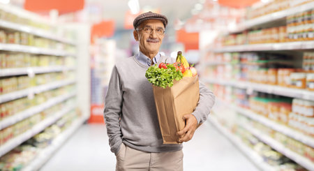 Senior man carrying a paper grocery bag in a supermarket aisleの写真素材