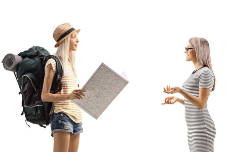 Female tourist with a backpack holding a map and talking to a woman isolated on white backgroundの写真素材