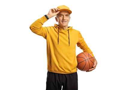 Cool senior man in a yellow hoodie holding a basketball isolated on a white backgroundの写真素材