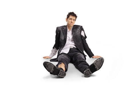 Man in a ruined suit sitting on the floor isolated on white background