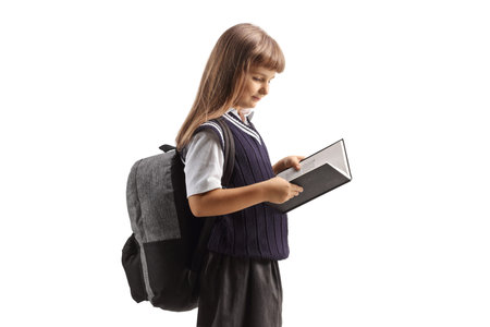 Child in a school uniform standing and reading a book isolated on white backgroundの写真素材