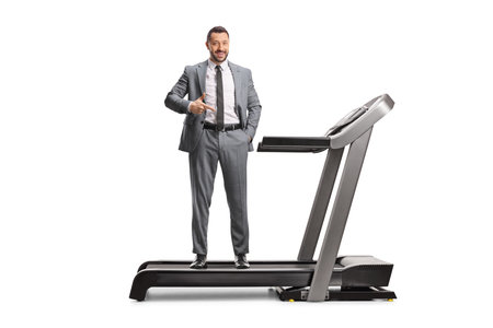 Man in a formal suit standing on a treadmill and pointing isolated on white background