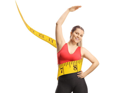 Young woman in sportswear with measure tape stretching upper body isolated on white background